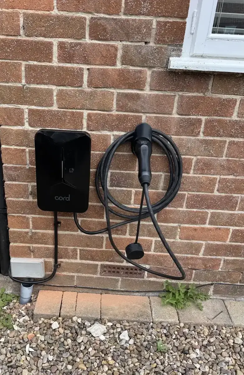 Black EV charger with neatly routed cable on a brick wall